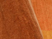 Nahaufnahme eines orangefarbenen Teppichs mit weicher Textur, teilweise aufgerollt.