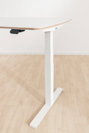 Moderner höhenverstellbarer Schreibtisch in Seitenansicht mit weißer Tischplatte und stabilem Metallgestell auf Holzfußboden.