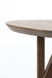 Nahaufnahme eines runden Esstisches aus Holz mit glatter Oberfläche und stabilen Beinen, seitliche Perspektive.