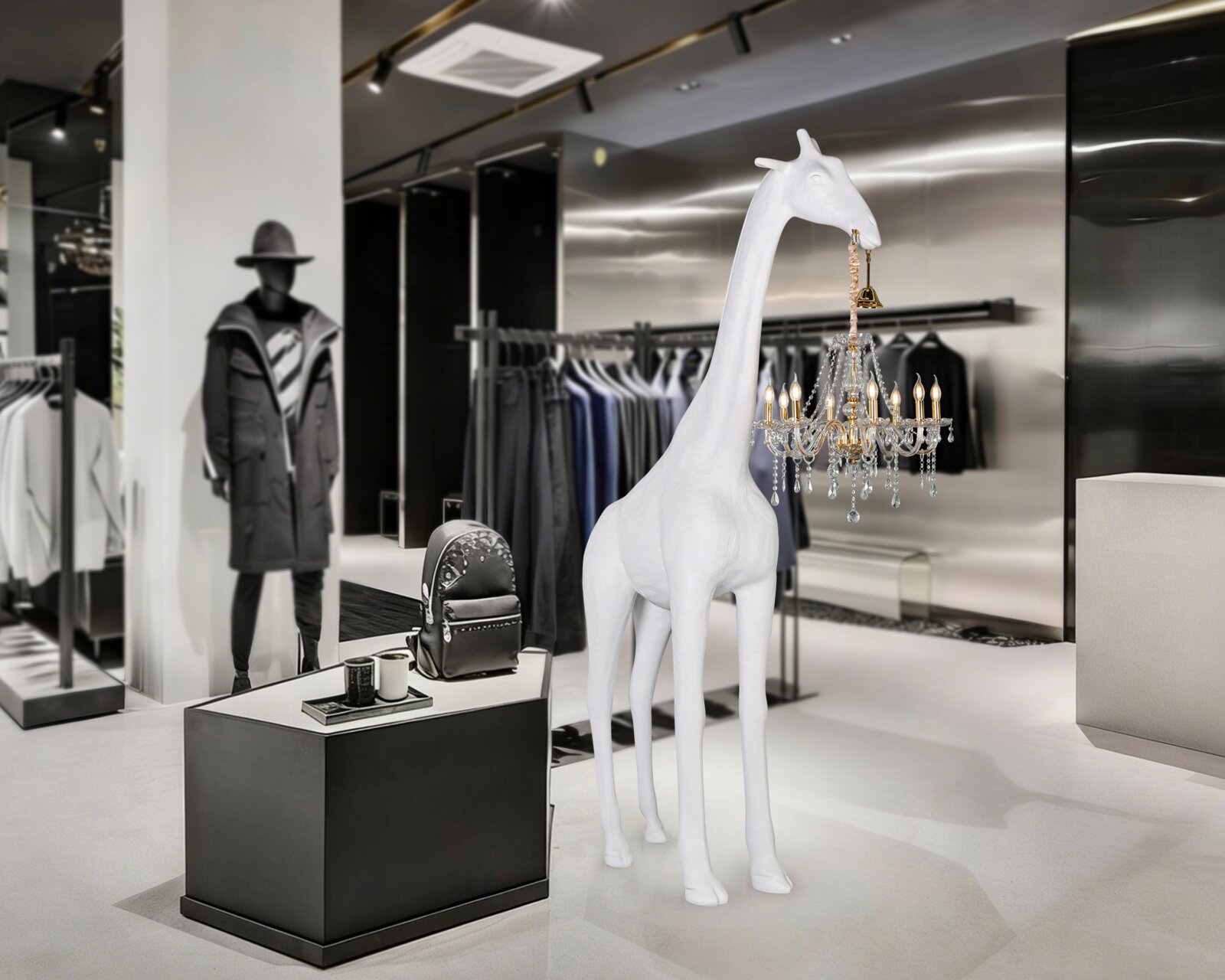 Weiße Giraffen-Skulptur als Designobjekt in einer Modeboutique, seitliche Frontansicht aus leicht erhöhter Perspektive am Hals hängt ein kleiner Kristall-Kronleuchter.