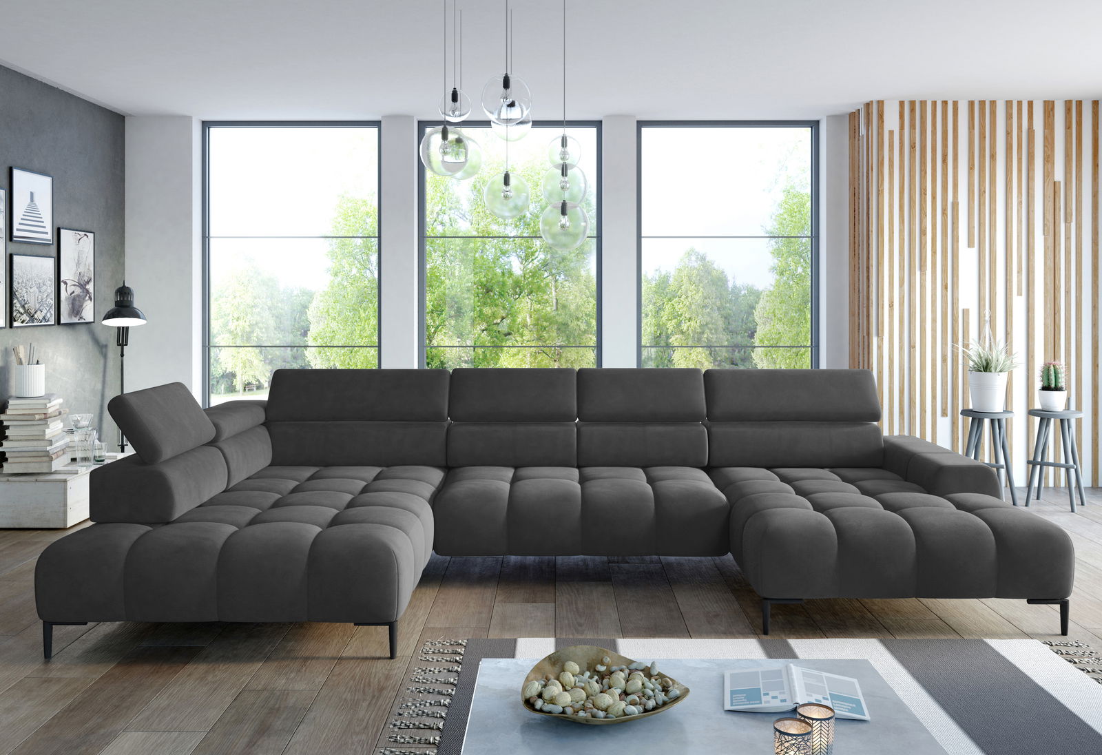 Große, moderne Polsterrundecke in dunklem Grau, perspektivisch von vorne fotografiert, in einem hellen Wohnzimmer mit großen Fenstern und stilvoller Dekoration.