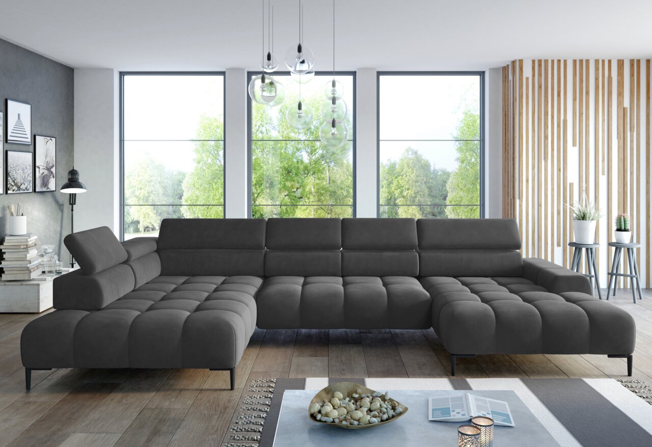 Große, moderne Polsterrundecke in dunklem Grau, perspektivisch von vorne fotografiert, in einem hellen Wohnzimmer mit großen Fenstern und stilvoller Dekoration.
