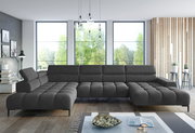 Große, moderne Polsterrundecke in dunklem Grau, perspektivisch von vorne fotografiert, in einem hellen Wohnzimmer mit großen Fenstern und stilvoller Dekoration.