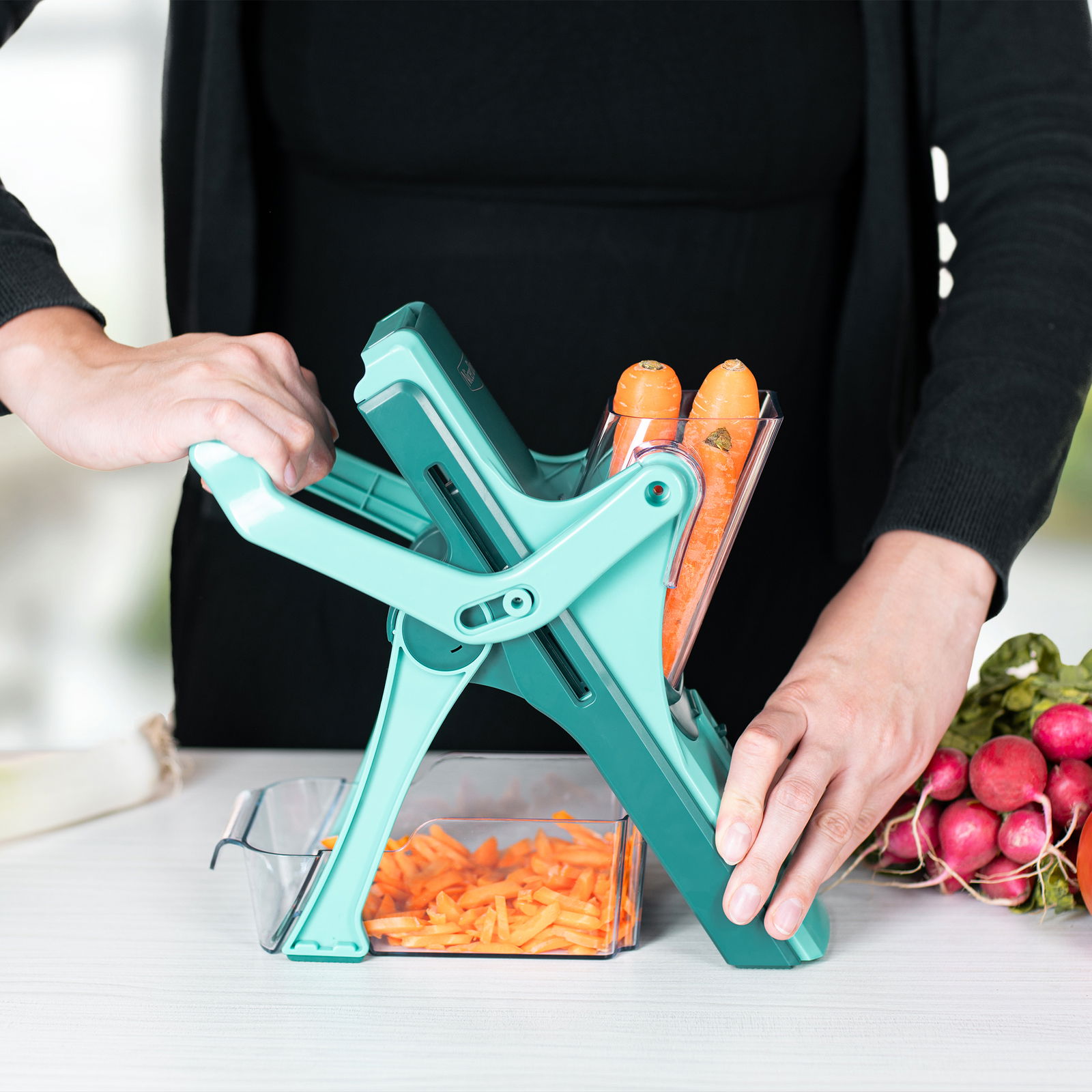 Nicer Dicer Mando, Set 10-tlg., in seitlicher Perspektive, während Karotten in Streifen geschnitten werden.