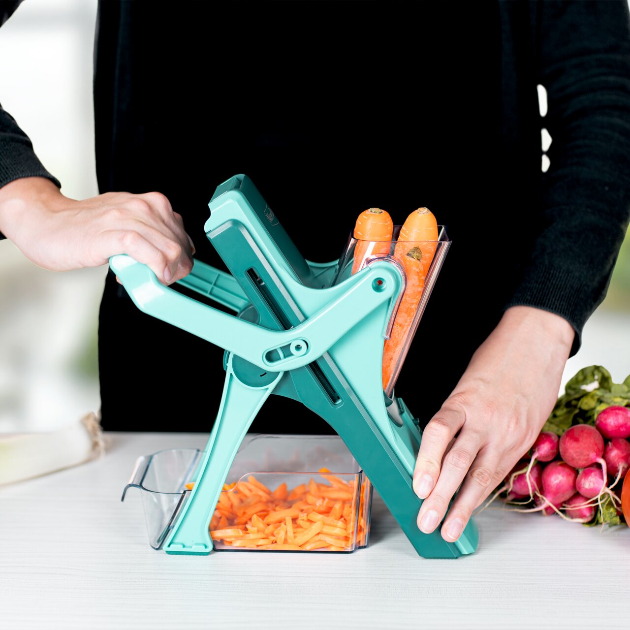 Nicer Dicer Mando, Set 10-tlg., in seitlicher Perspektive, während Karotten in Streifen geschnitten werden.