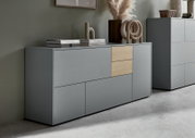 Modernes Sideboard in Grau mit zwei Holzelementen, dekoriert mit Büchern und Skulpturen, seitliche Perspektive.