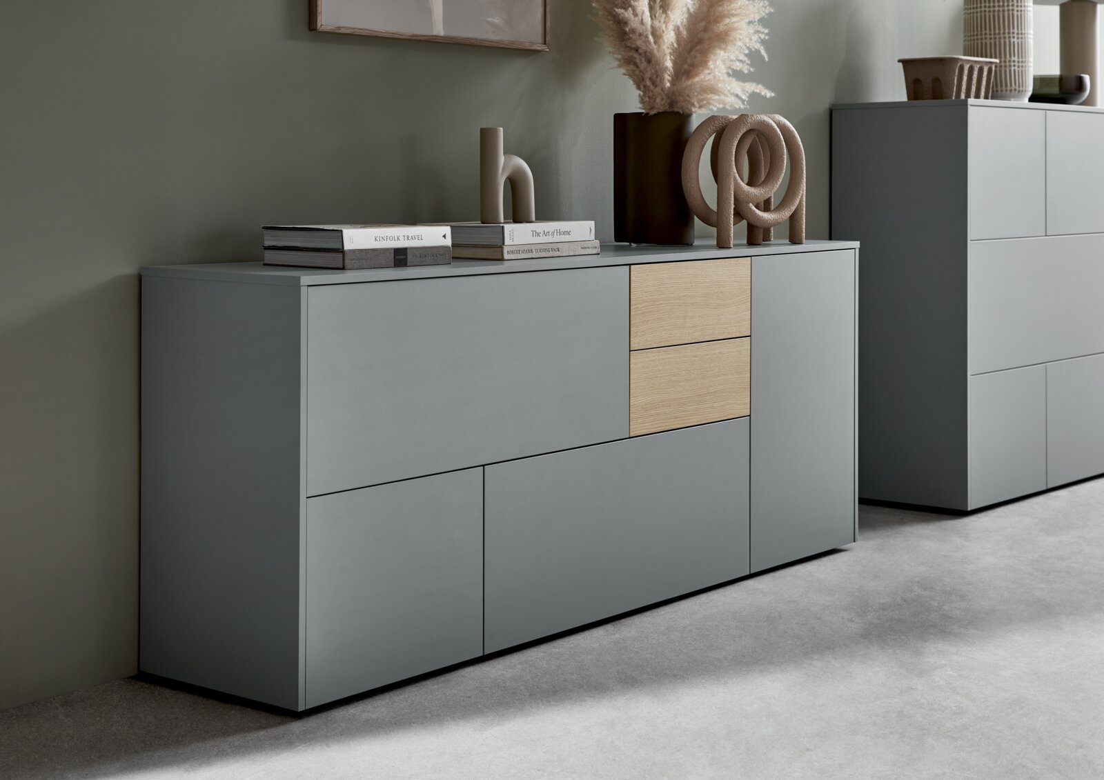 Modern dressoir in grijs met twee houten elementen, versierd met boeken en beeldjes, zijaanzicht.
