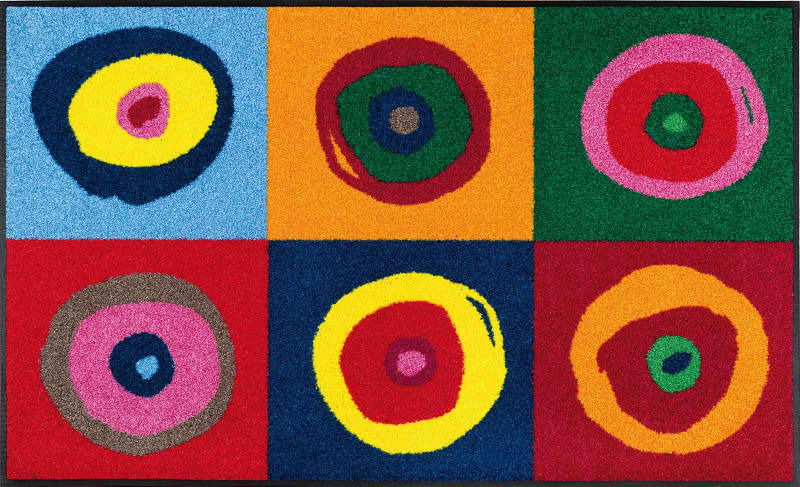 Bunte Fußmatte mit sechs farbigen Kreisen auf einem rechteckigen Hintergrund, aus der Vogelperspektive fotografiert.