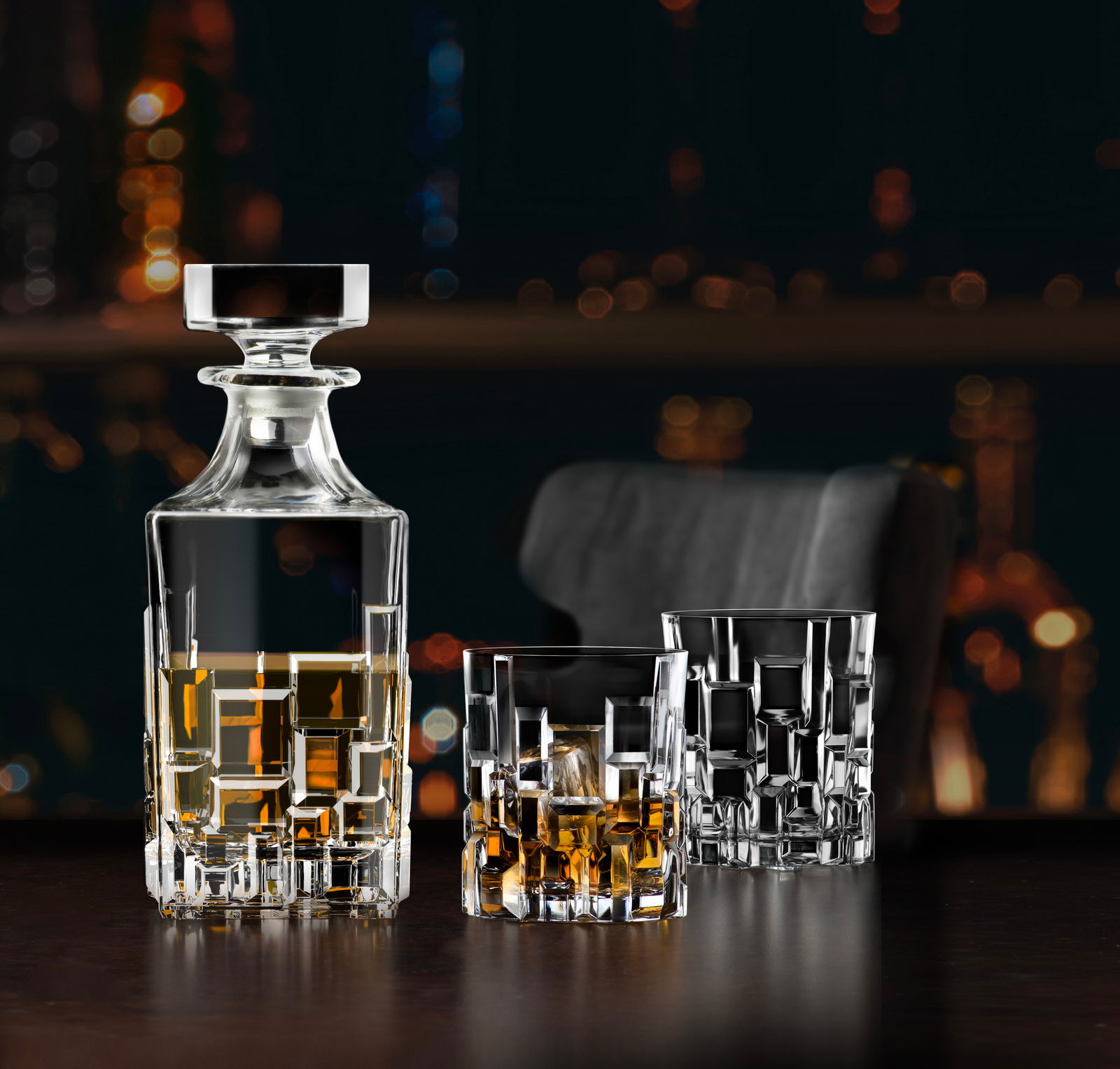 Elegantes Barset Etna 7-tlg. mit Kristallkaraffe und zwei Gläsern, gefüllt mit Whisky, auf einem dunklen Tisch vor unscharfem Hintergrund. Perspektive: seitlich.