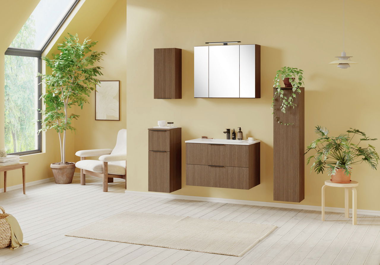 Moderner Badezimmer-Unterschrank in Holzoptik, frontal betrachtet, in einem hellen Raum mit Pflanzen und großen Fenstern.