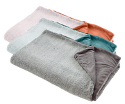 Vier übereinander liegende Felldecken in verschiedenen Farben, von oben nach unten: Rosa, Türkis, Grau und Orange. Perspektive von oben.