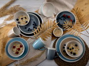 Vogelperspektive auf ein stilvolles Kombiservice-Set 'Nordic Living' mit Tellern, Schalen und Tassen in sanften Blau- und Beigetönen, dekoriert mit Müsli und Beeren.