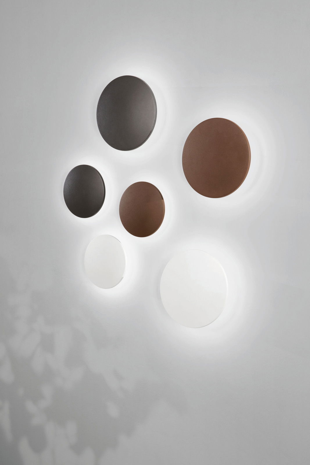 LED-Außenwandleuchten in verschiedenen Farben und Größen, an einer Wand montiert, mit leuchtendem Halo-Effekt. Perspektive von vorne.