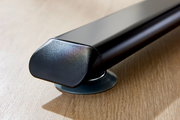 Nahaufnahme eines schwarzen Tischbeins mit runder Basis auf Holzoberfläche, seitliche Perspektive