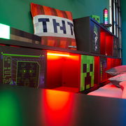 Jugendbett mit Minecraft-Thema, bunte LED-Beleuchtung und dekorativen Kissen, seitliche Perspektive