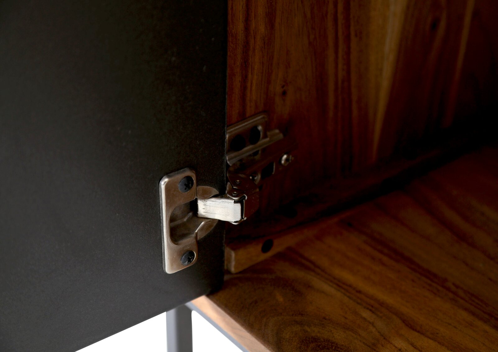 Nahaufnahme eines Scharniers an einem Lowboard aus Holz und Metall, von innen betrachtet.
