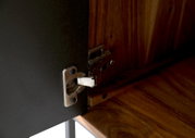 Nahaufnahme eines Scharniers an einem Lowboard aus Holz und Metall, von innen betrachtet.