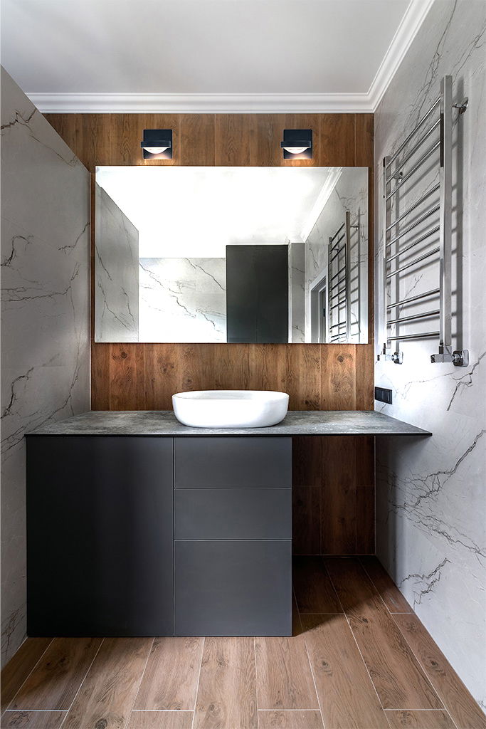 Megatron LED-Wandleuchte SOLO PUNTO - DOWN Moderne LED-Wandleuchte SOLO PUNTO - DOWN über einem großen Spiegel in einem stilvollen Badezimmer mit Holz- und Marmorelementen, frontal betrachtet.