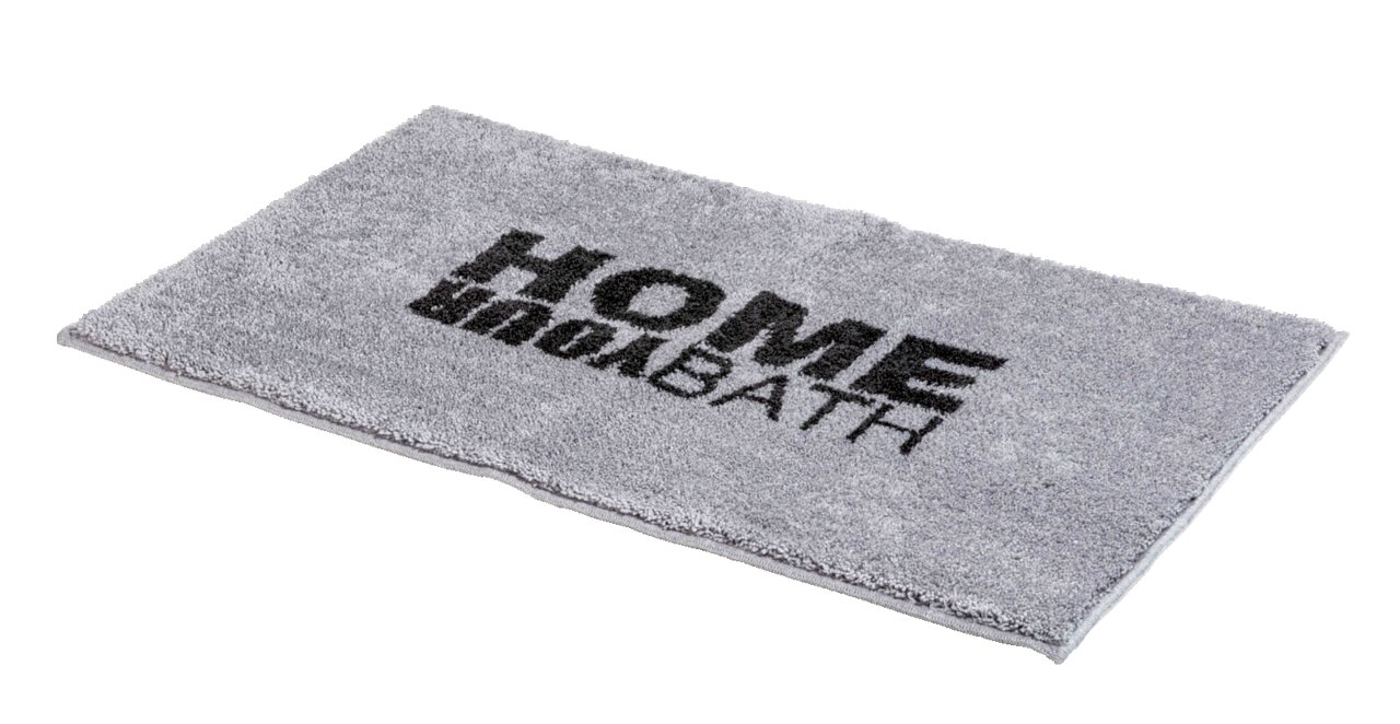 Grauer Badteppich mit der Aufschrift 'HOME BATH', schräg von oben fotografiert.