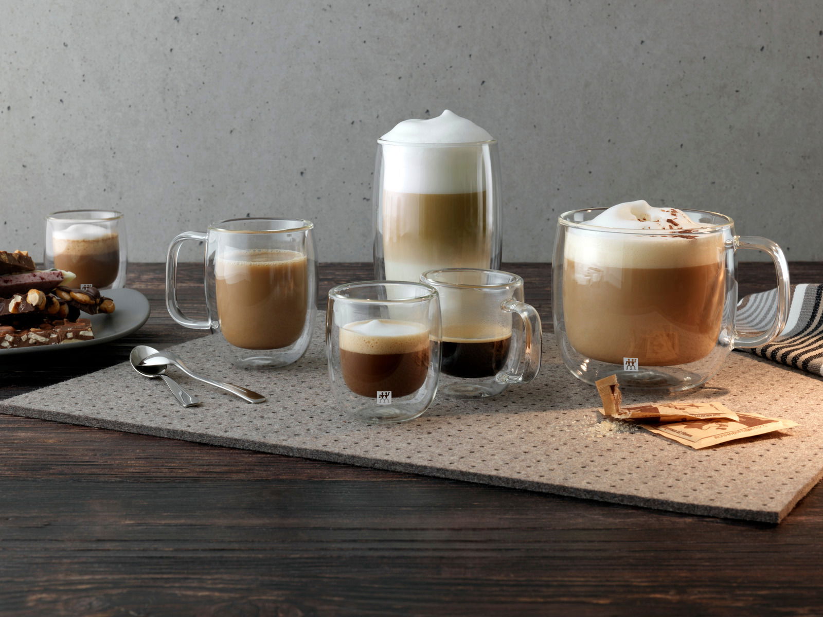 Verschiedene Gläser mit Kaffeegetränken auf einem Tisch, darunter ein Cappuccinoglas-Set mit 450 ml Fassungsvermögen, seitliche Perspektive.