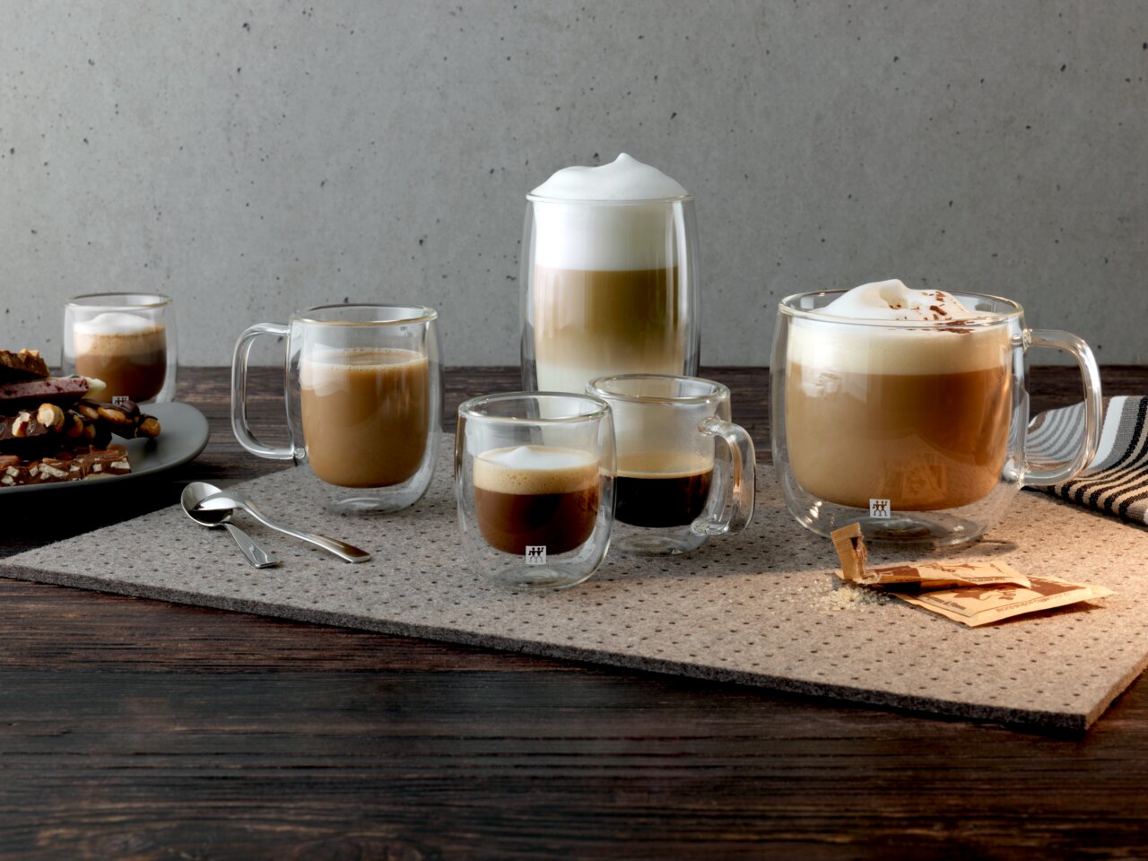 Verschiedene Gläser mit Kaffeegetränken auf einem Tisch, darunter ein Cappuccinoglas-Set mit 450 ml Fassungsvermögen, seitliche Perspektive.