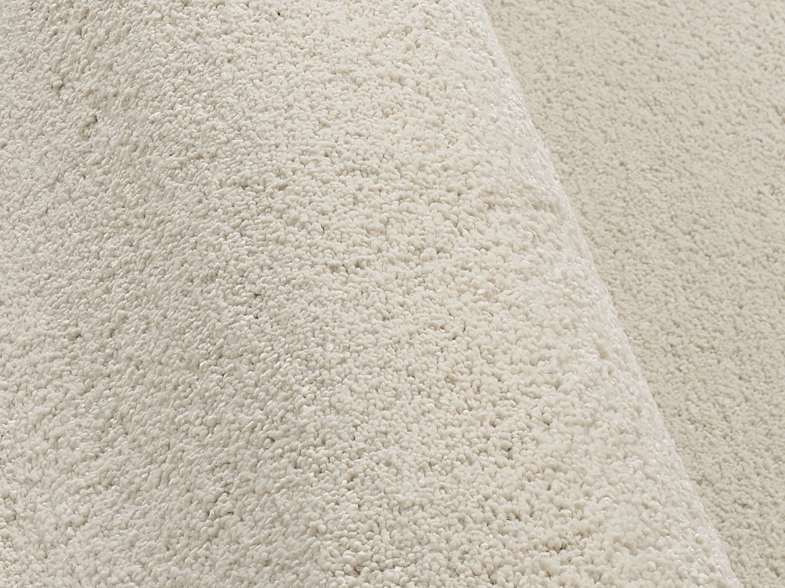 Nahaufnahme eines cremefarbenen Uni-Teppichs mit weicher Textur, seitliche Perspektive