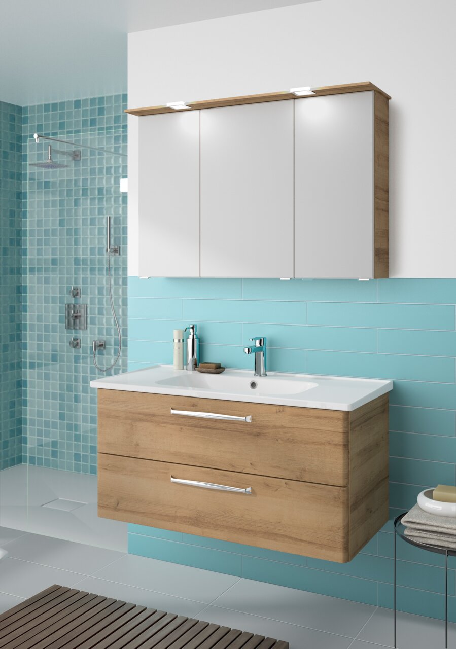 Modern badkamermeubel met houtlook en een witte wastafel, gezien vanaf de voorkant, tegen een turquoise muur.