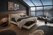 Modernes Polsterbett in einem stilvollen Schlafzimmer mit Panoramafenster und Blick auf das Meer, seitliche Perspektive.