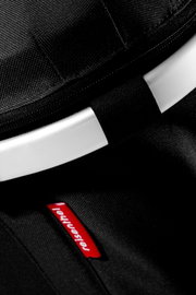 Close-up schuin bovenaanzicht van een zwarte Reisenthel tas met witte handgreep/boog en rood Reisenthel label op de stof