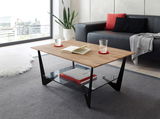 Moderner Couchtisch mit Holzplatte und schwarzem Metallgestell, seitliche Perspektive. Unter der Tischplatte befindet sich eine Glasablage mit Büchern.