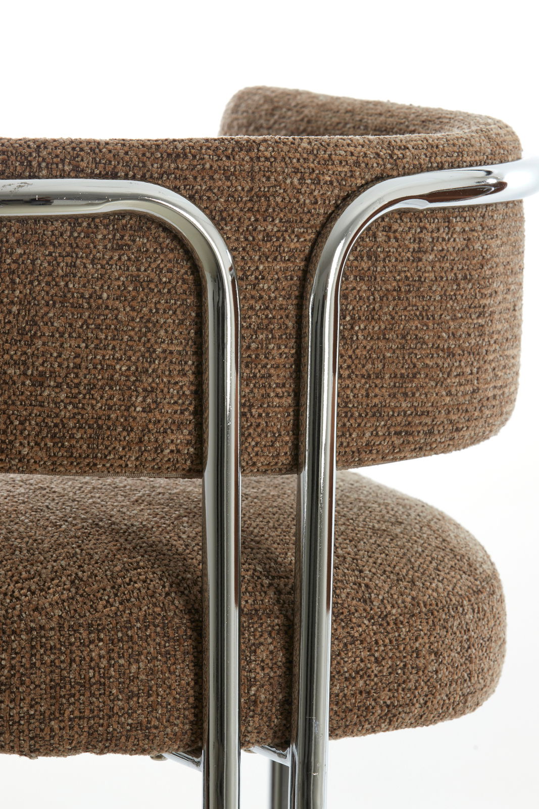 Nahaufnahme eines Armlehnstuhls mit braunem Stoffbezug und verchromtem Metallrahmen, seitliche Perspektive.