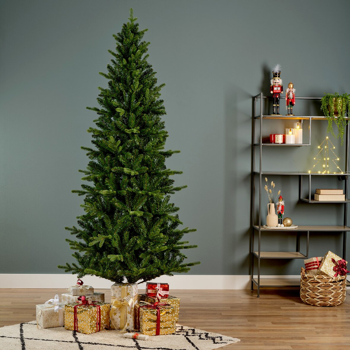 Een kunstkerstboom in een woonkamer, omringd door cadeautjes, gezien vanuit een zijdelingse hoek.