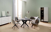 Moderner Esstisch in einem stilvollen Wohnzimmer mit grüner Wand, umgeben von eleganten Stühlen und einem Sofa, aus seitlicher Perspektive betrachtet.