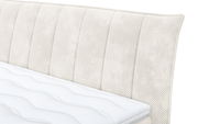 Nahaufnahme eines Boxspringbetts mit gepolstertem Kopfteil in cremefarbener Textur, seitliche Perspektive