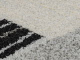 Nahaufnahme eines Webteppichs mit geometrischem Muster in Schwarz, Weiß und Grau. Die Perspektive zeigt die Textur und das Design des Teppichs aus der Nähe.