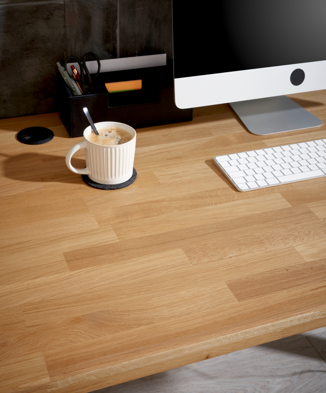 Holzschreibtisch mit Computer, Tastatur und Kaffeetasse aus der Vogelperspektive