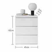 Weiße Nachtkommode mit drei Schubladen, darauf eine Lampe und ein Buch, frontale Ansicht, Maße: 62cm hoch, 45cm breit, 38cm tief.