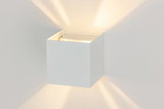 Moderne LED-Wandleuchte in Würfelform, die warmes Licht nach oben und unten abstrahlt, seitliche Perspektive.