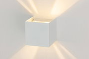 Moderne LED-Wandleuchte in Würfelform, die warmes Licht nach oben und unten abstrahlt, seitliche Perspektive.