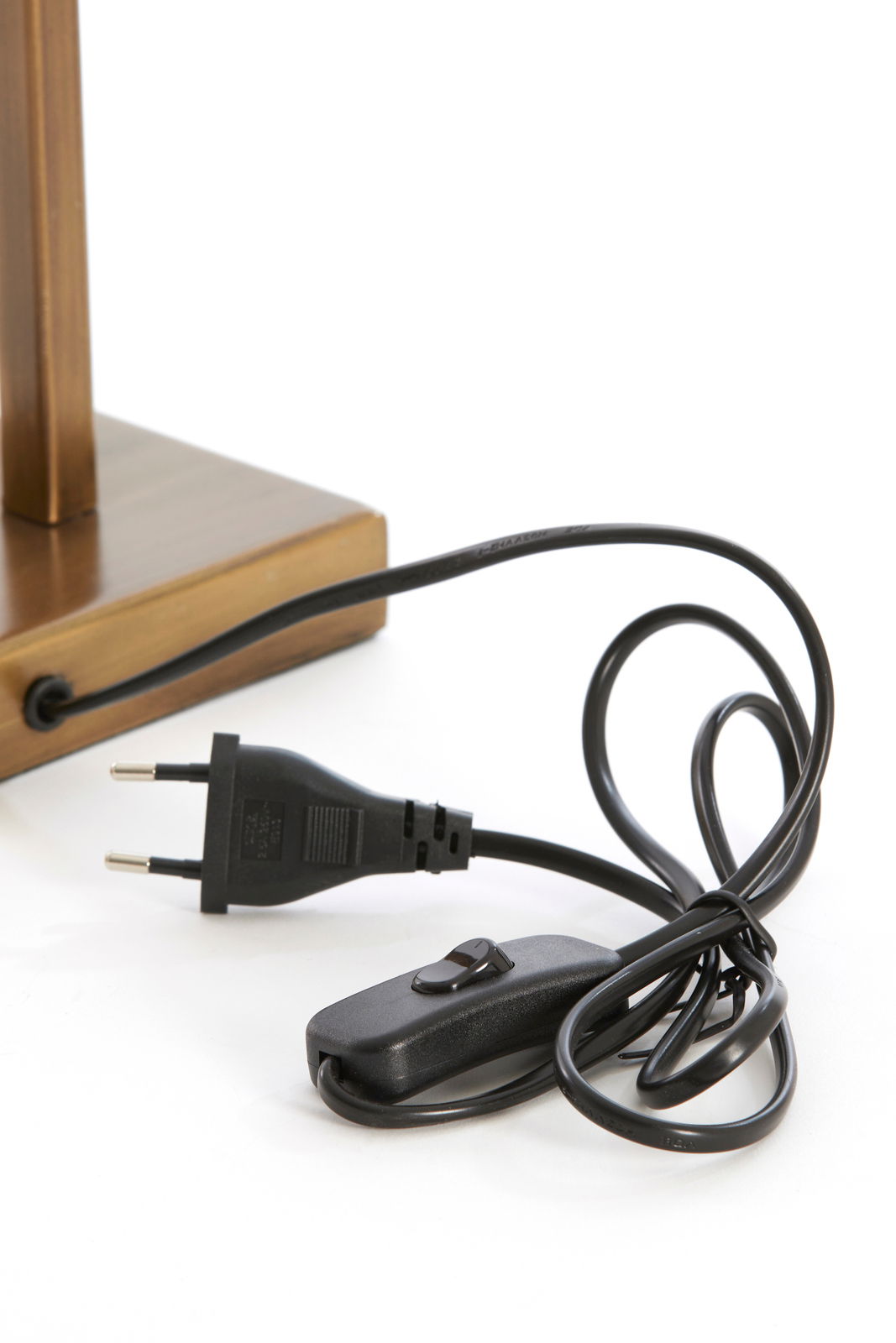 Nahaufnahme eines Lampenfußes mit einem schwarzen Kabel und einem Schalter, perspektivisch von der Seite aufgenommen.