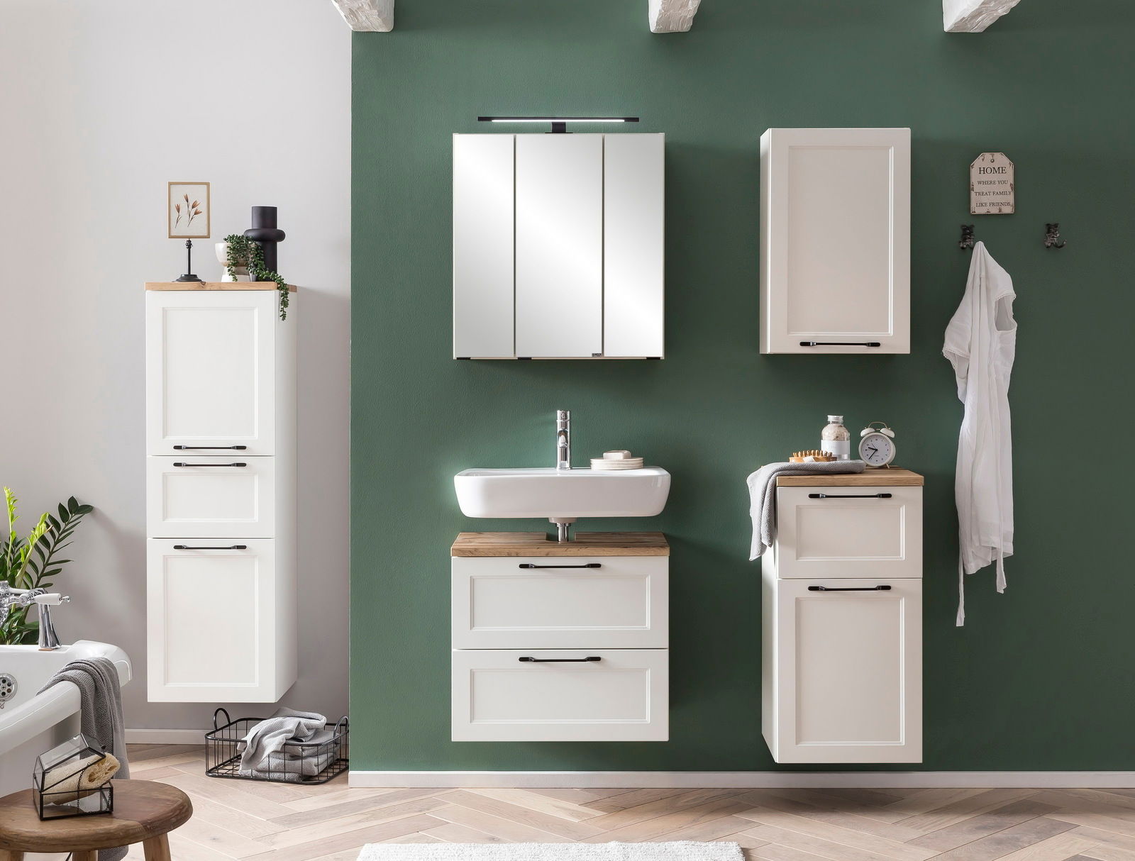 Moderner weißer Midischrank in einem stilvollen Badezimmer, frontal betrachtet, mit grüner Wand im Hintergrund.