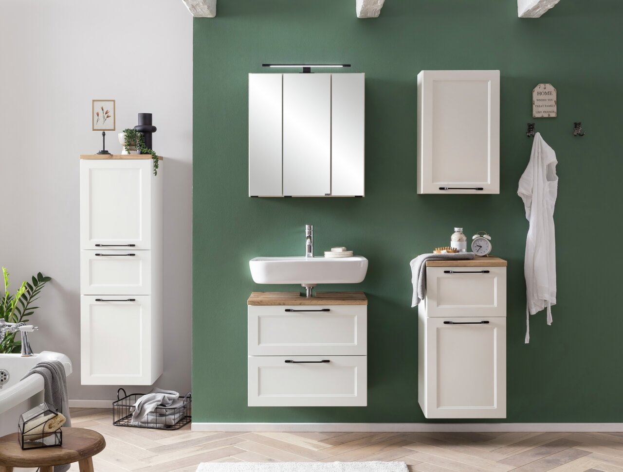 Moderner weißer Midischrank in einem stilvollen Badezimmer, frontal betrachtet, mit grüner Wand im Hintergrund.