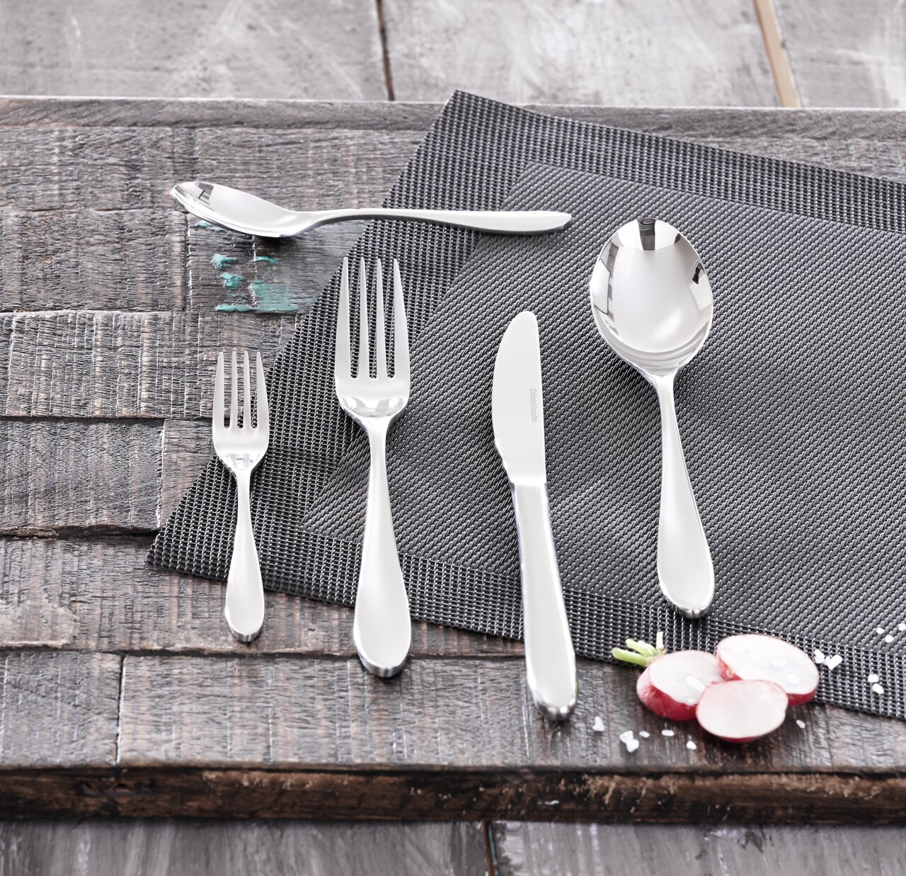 Besteckset bestehend aus Messer, Gabel, Löffel und Teelöffel auf einem grauen Platzdeckchen, von oben fotografiert.