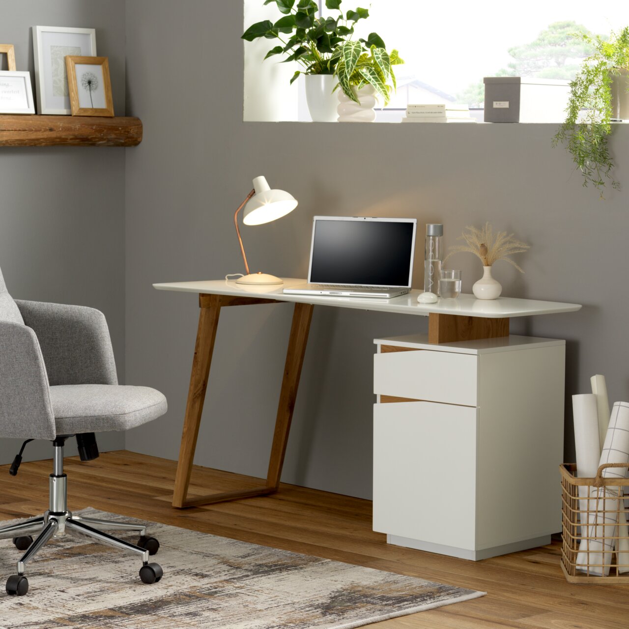 Moderner Schreibtisch mit weißer Tischplatte und Holzbeinen, seitlich mit Schubladenelement, aus der Perspektive eines gemütlichen Home-Office.
