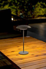 Moderne Akku-Tischleuchte SARDINIA auf einem Holztisch, seitliche Perspektive, ideal für stimmungsvolle Beleuchtung im Freien.