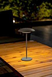 Moderne Akku-Tischleuchte SARDINIA auf einem Holztisch, seitliche Perspektive, ideal für stimmungsvolle Beleuchtung im Freien.