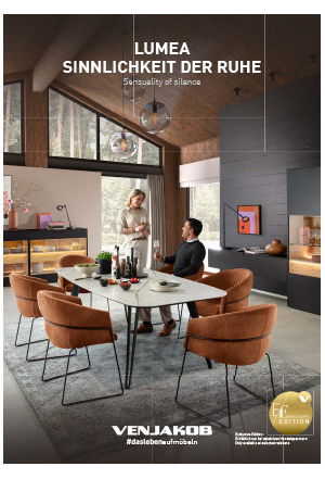 Ein modernes Esszimmer mit rundem Tisch, beigen Stühlen, Kamin und großen Fenstern mit Waldblick.