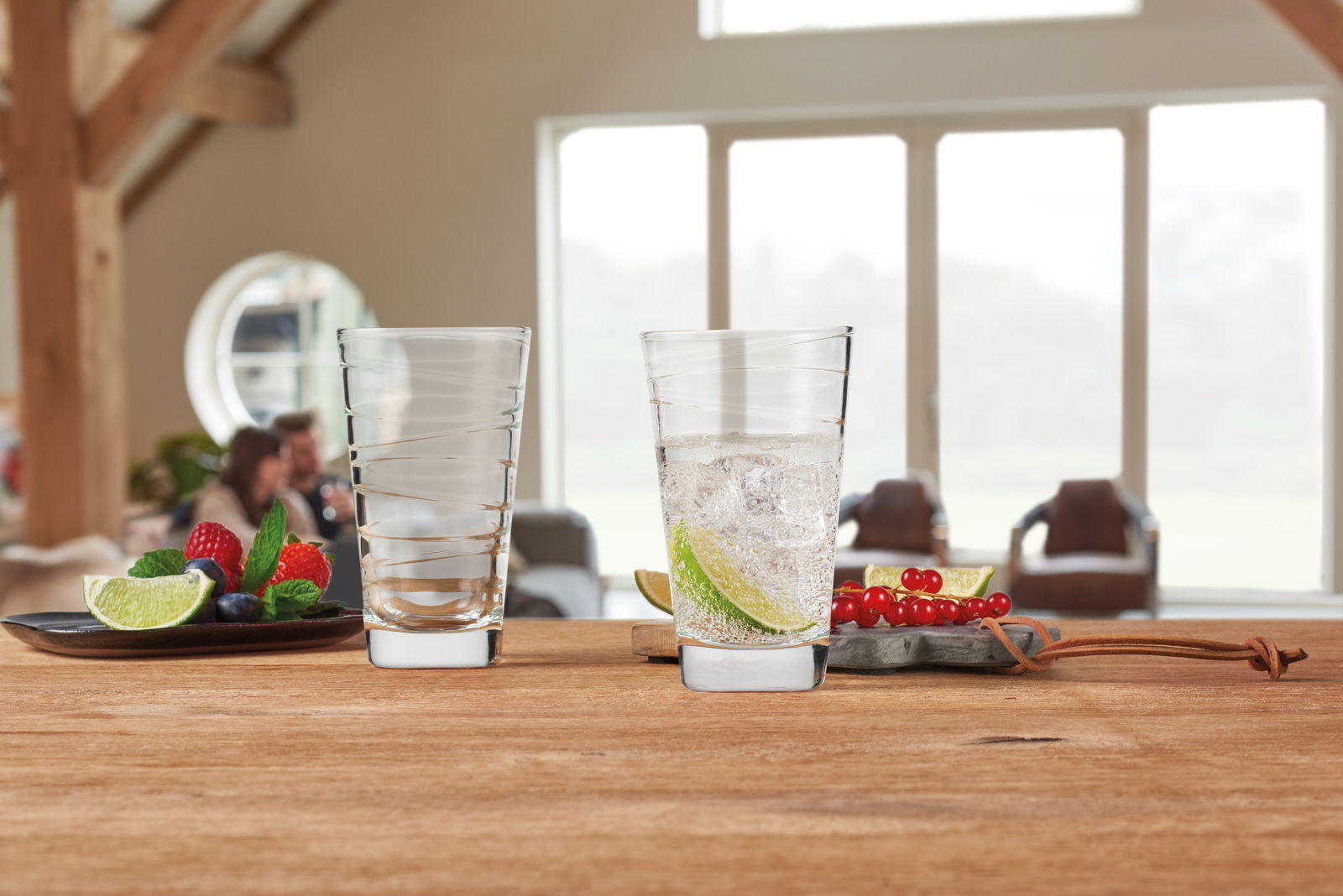 Leonardo Trinkglas VARIO Zwei Trinkgläser Vario 280ml von Leonardo auf einem Holztisch, eines gefüllt mit einem Getränk und Limettenscheiben, im Hintergrund ein gemütlicher Wohnraum.