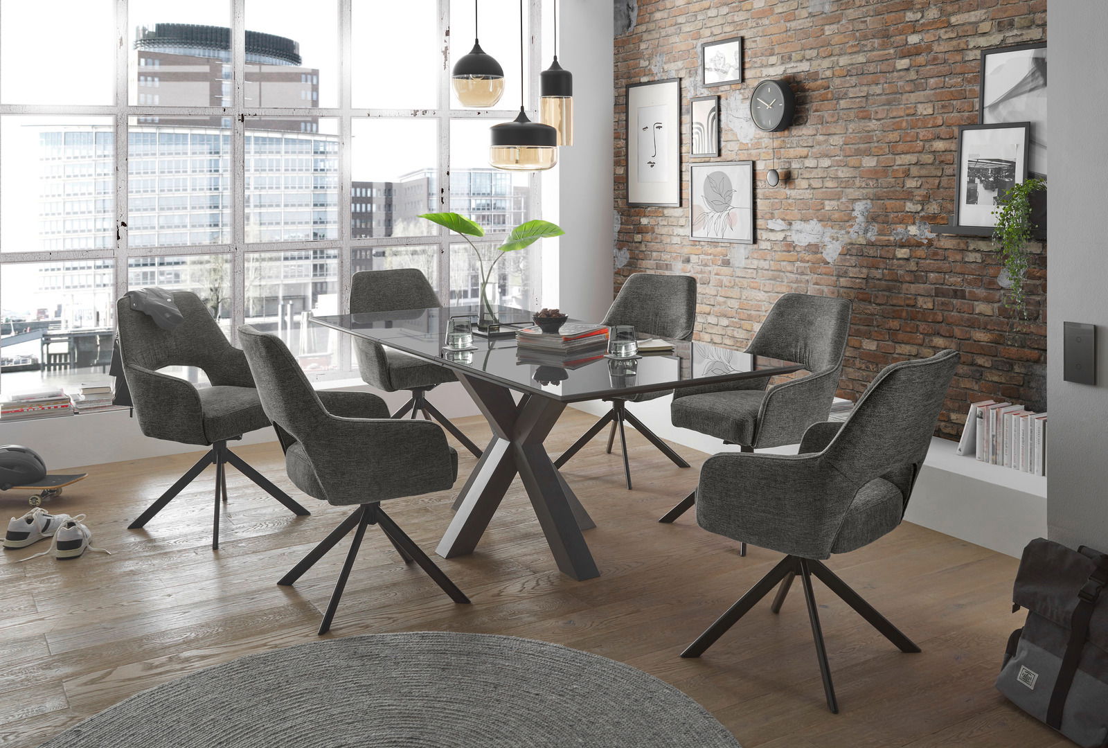 Moderner Essbereich mit sechs grauen Armlehnstühlen um einen Glastisch, aus der Perspektive von schräg vorne fotografiert.