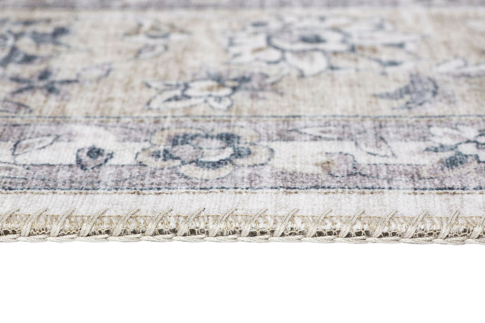 Nahaufnahme eines Teppichs mit floralen Mustern und sichtbarer Kante, seitliche Perspektive